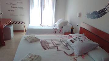 Une chambre d’hôtel avec deux lits, un bureau et une chaise. Il y a des serviettes sur les lits et une décoration en plumes accrochée au mur.