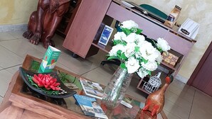A wooden coffee table with a glass top, surrounded by a wooden cabinet, a lion statue, and a framed picture on the wall.