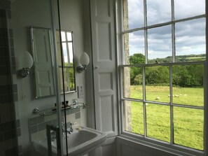 A bathroom with a large window, a sink, and a mirror. - The Old Vicarage at Oakridge (Stroud)