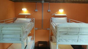 Dos camas literas con lámparas de noche incorporadas, un escalón pequeño entre ellas y un enchufe de pared.