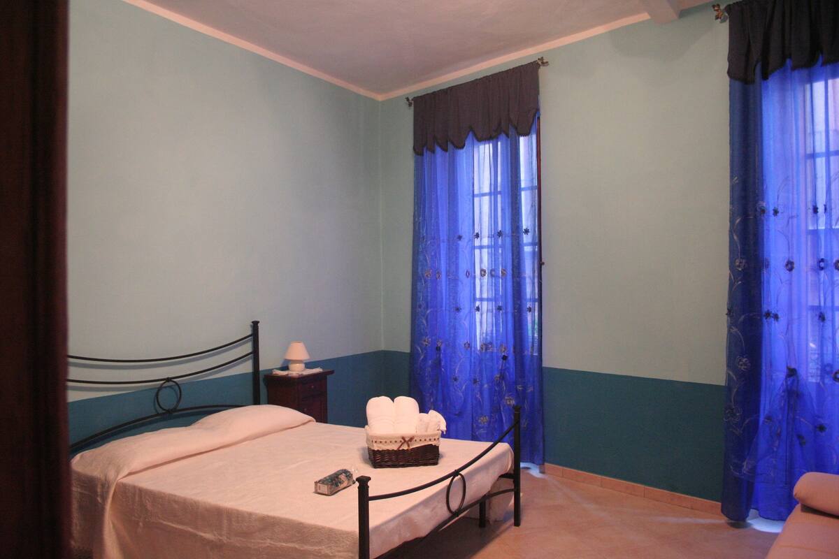Un dormitorio con una cama individual, una mesita de noche y una ventana con cortinas azules.