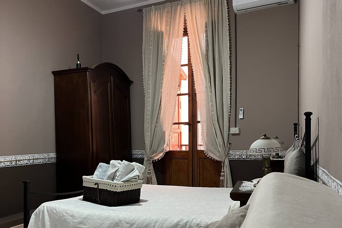 Un dormitorio con dos camas, un armario de madera, una mesita de noche y una ventana con cortinas.