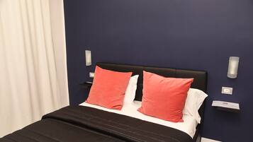 A bed with a black headboard, two red pillows, and a black bedspread.
