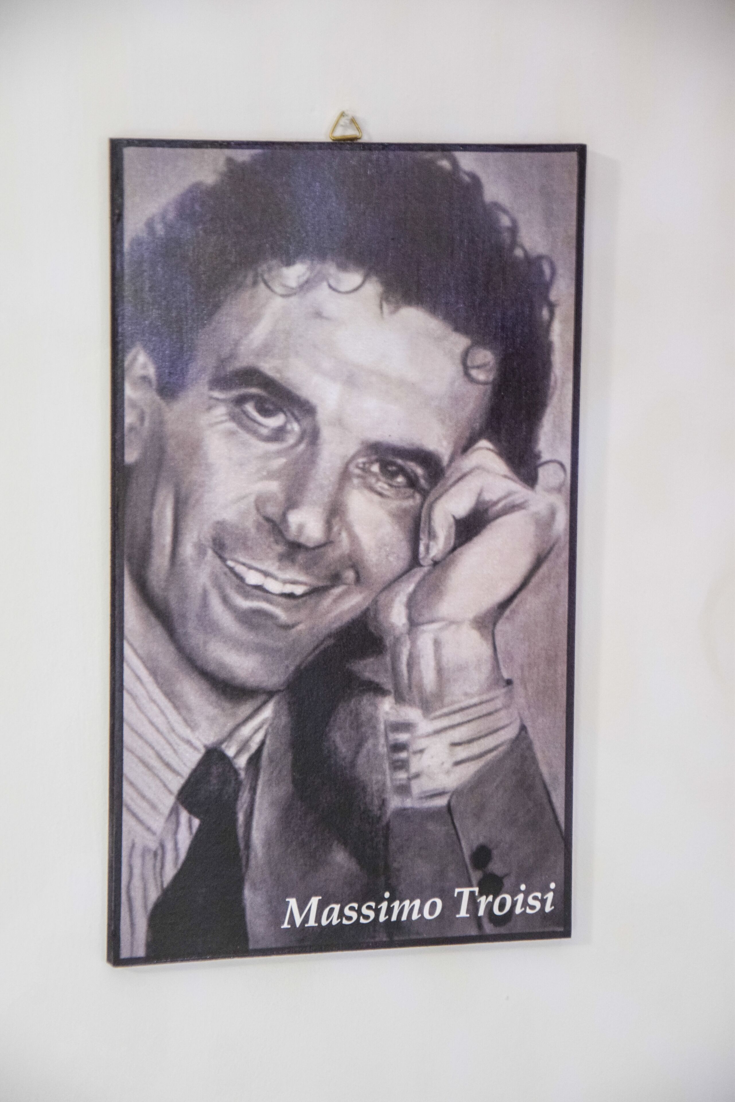 Un portrait encadré de Massimo Troisi, avec une légende en bas.