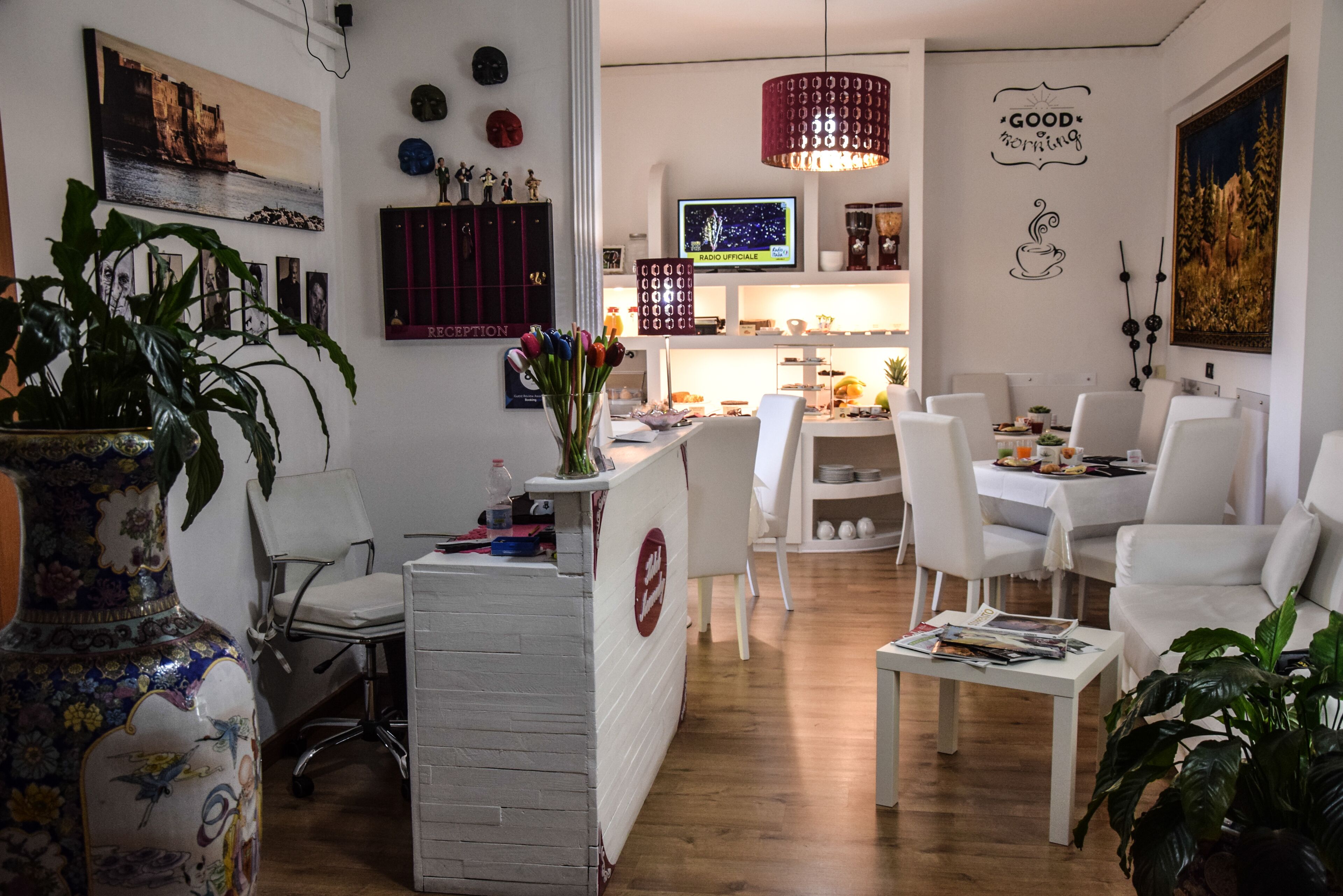Un salon moderne comprenant un coin repas, des meubles blancs, un téléviseur et des éléments décoratifs sur les murs.