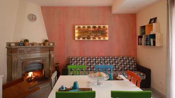 Un rincón comedor acogedor con chimenea, un banco y una mesa lista para disfrutar de una comida.