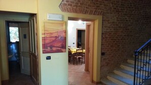 Un pasillo con una zona de comedor al fondo, una escalera y una pared de ladrillo.