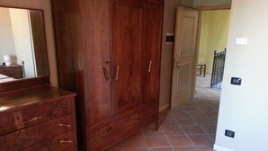 Una habitación con un armario de madera, un aparador y piso de baldosas.