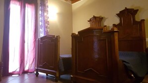Una habitación con muebles de madera, una cama y un ventanal con cortinas.
