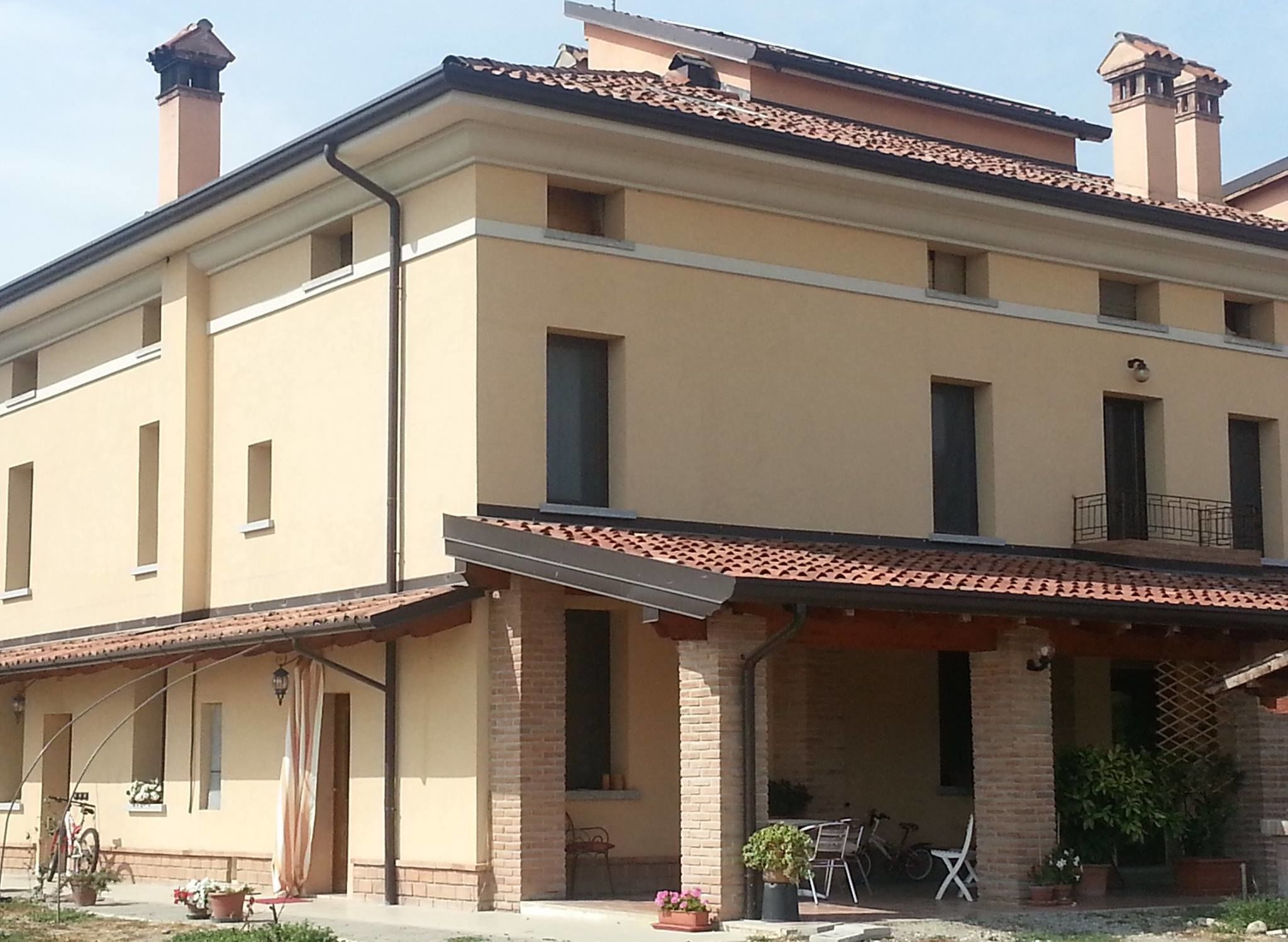 A two-story building with a flat roof, multiple windows, and a covered patio area with outdoor seating.