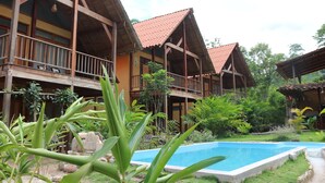 A resort with multiple wooden buildings, a swimming pool, and lush greenery. - Canto del Rio Lodge (San Antonio de Cumbaza)