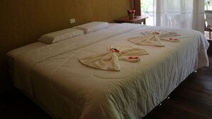 A hotel room with a large bed, a small table with a vase of flowers, and a window with curtains. - Canto del Rio Lodge (San Antonio de Cumbaza)