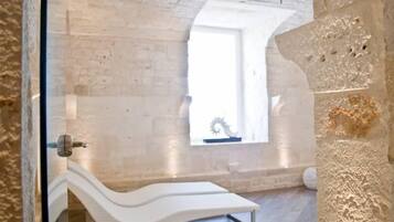 Relax in a serene space with a curved bench against a textured wall, a small window, and a focus on natural materials.