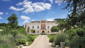 A large, two-story building with a symmetrical facade, a central entrance, and a paved pathway leading to it.