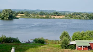 A lakeside view with a red building, a gazebo, and a person playing a guitar.