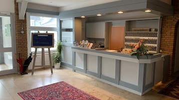 A reception area with a reception desk, a chalkboard with greetings, a potted plant, and a tiled floor.