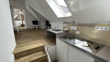 Una cocina moderna con tragaluz, escalera de madera y zona de comedor con mesa y sillas.