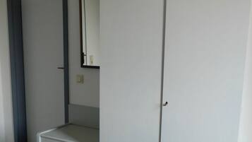 Une chambre à coucher avec un lit, une armoire, un miroir et un petit bureau.