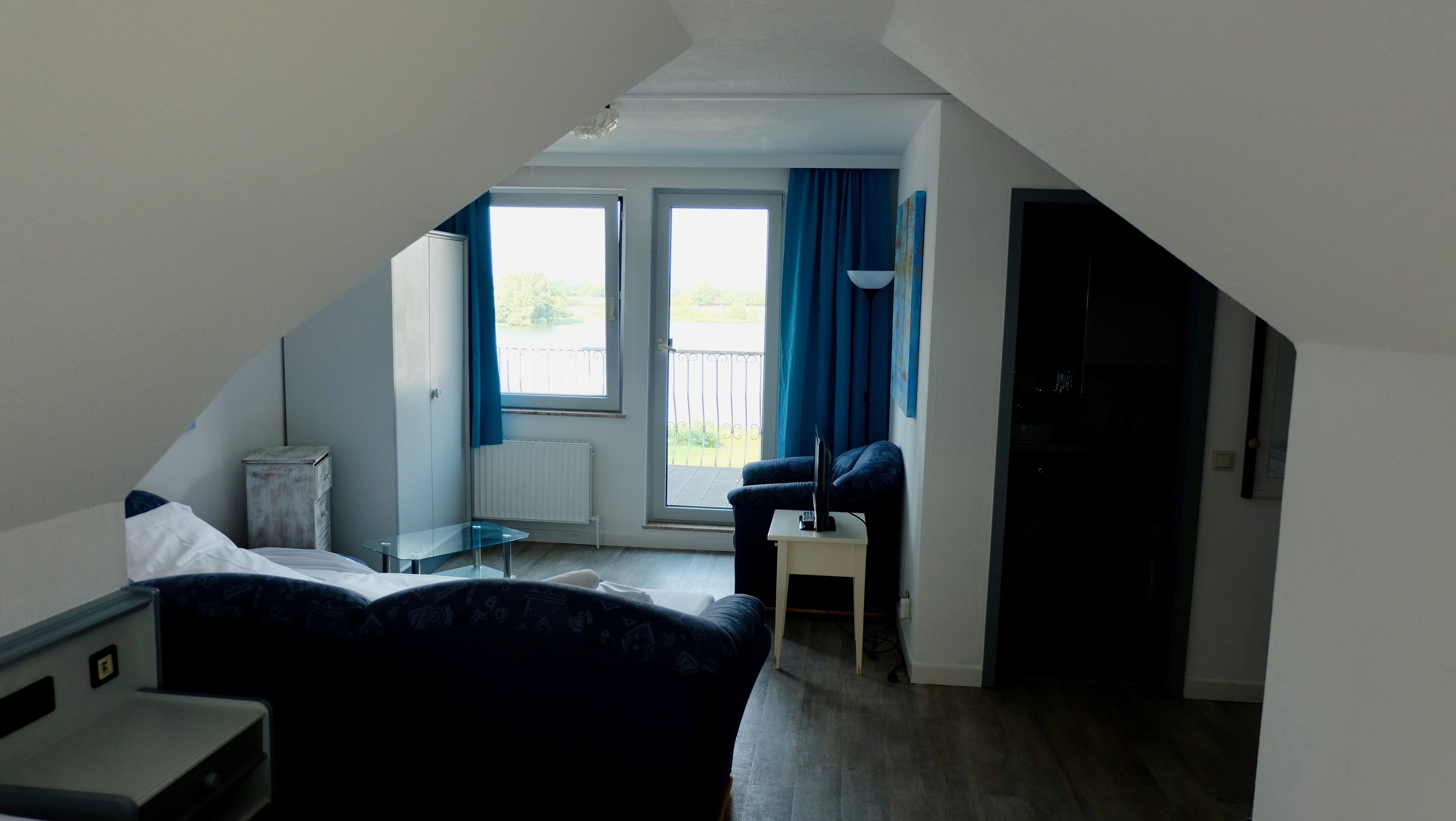A modern bedroom with a bed, a small table, a chair, and a balcony with a view.