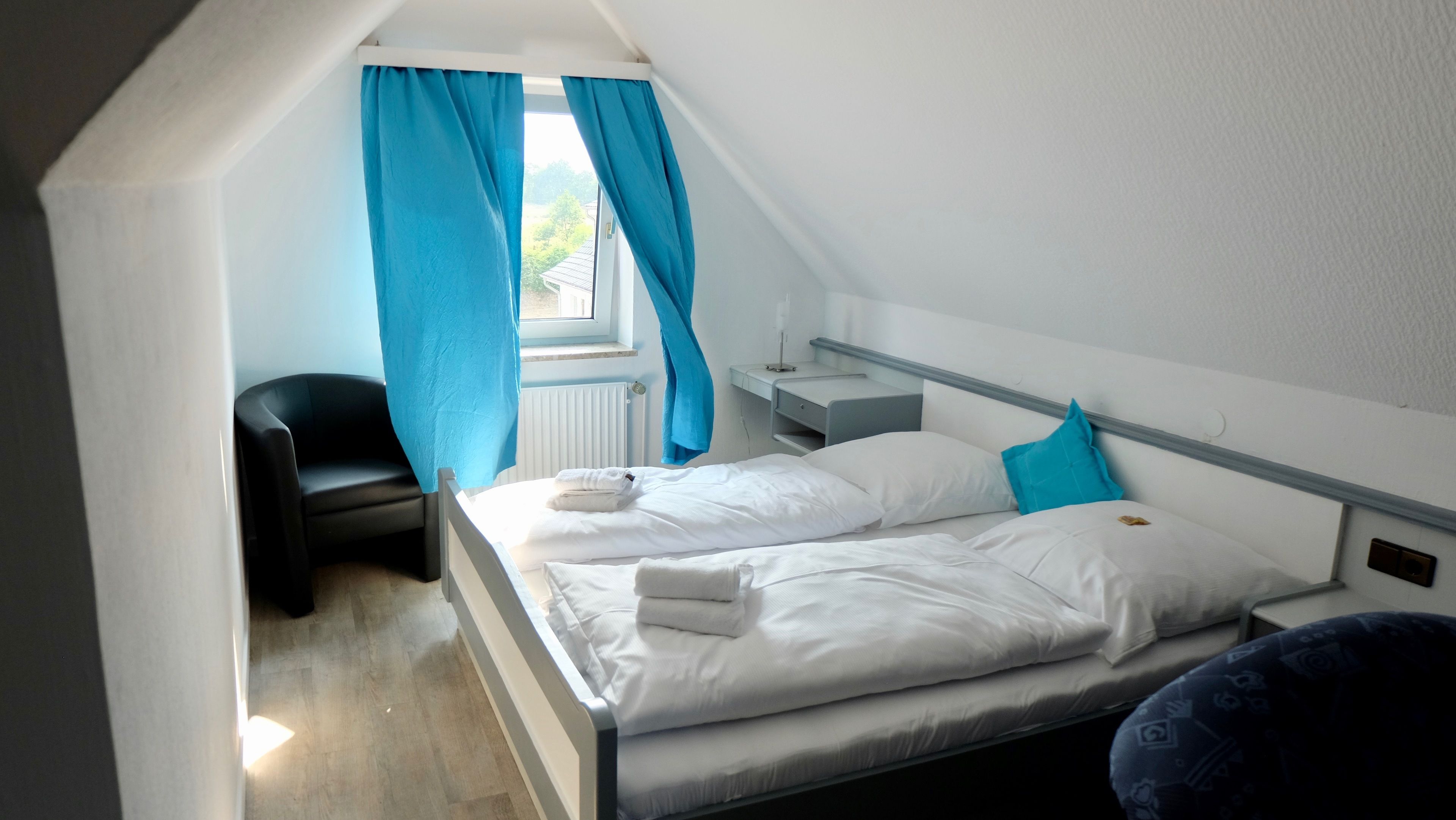 A bedroom with two beds, a desk, a chair, and a window with curtains.
