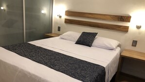 A modern hotel room with a large bed, wooden headboard, bedside tables, and wall-mounted lighting. - Hotel 15 Avenida (Tapachula)