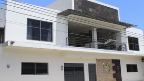 A modern two-story building with a balcony, large windows, and a garage door. - Hotel 15 Avenida (Tapachula)