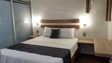 Une chambre à coucher comprenant un lit, des tables de chevet, une tête de lit en bois et un luminaire fixé au mur.