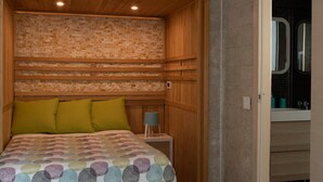 A bedroom with a patterned bedspread, wooden headboard, and a nightstand with a lamp. - B&B il giardino di Agata (Mascalucia)