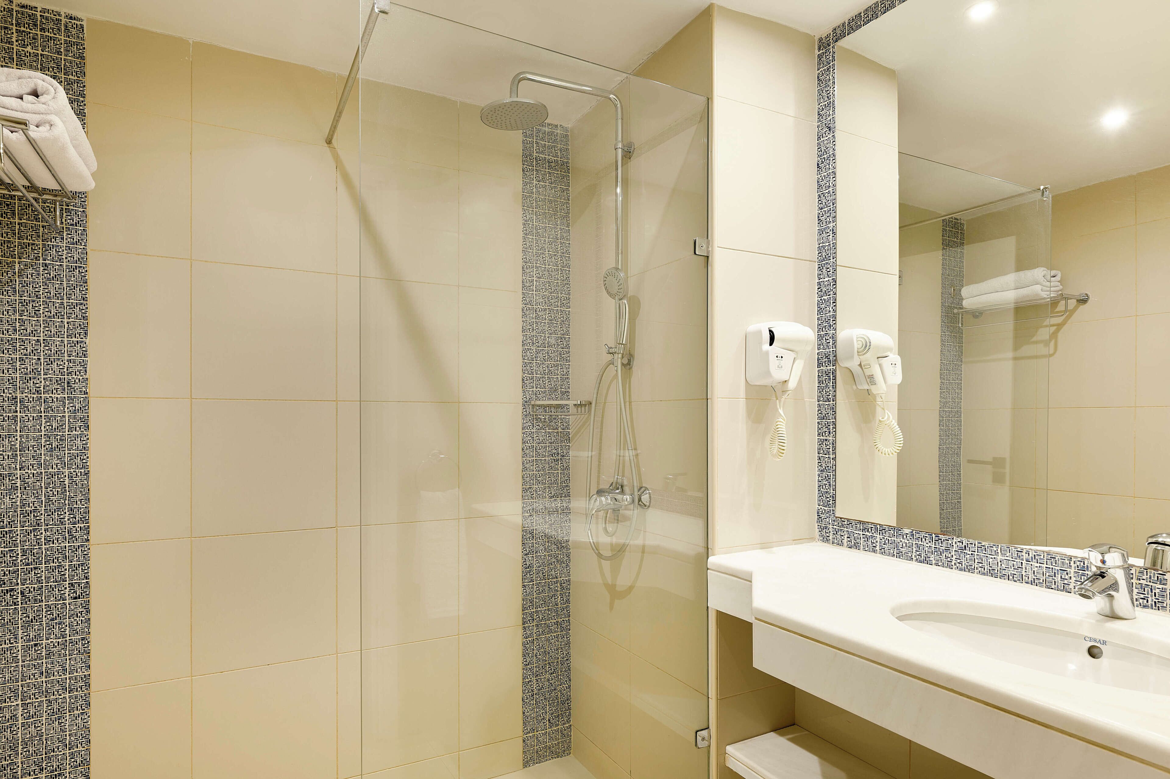 Un baño con ducha, lavabo y espejo.