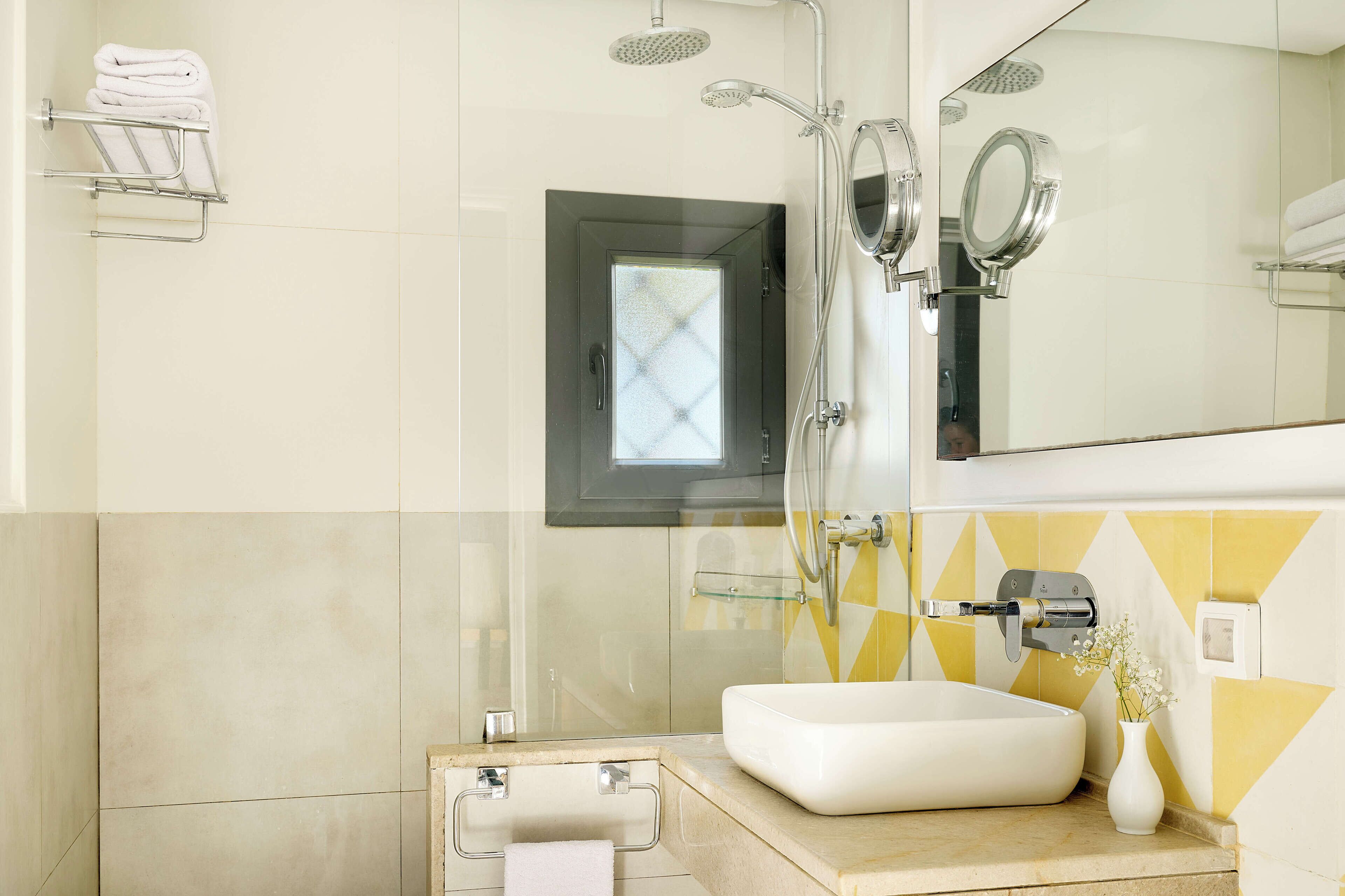 Un bagno moderno con uno specchio grande, un lavandino bianco e una zona doccia.