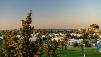 A coastal resort with white buildings, palm trees, and a view of the sea.