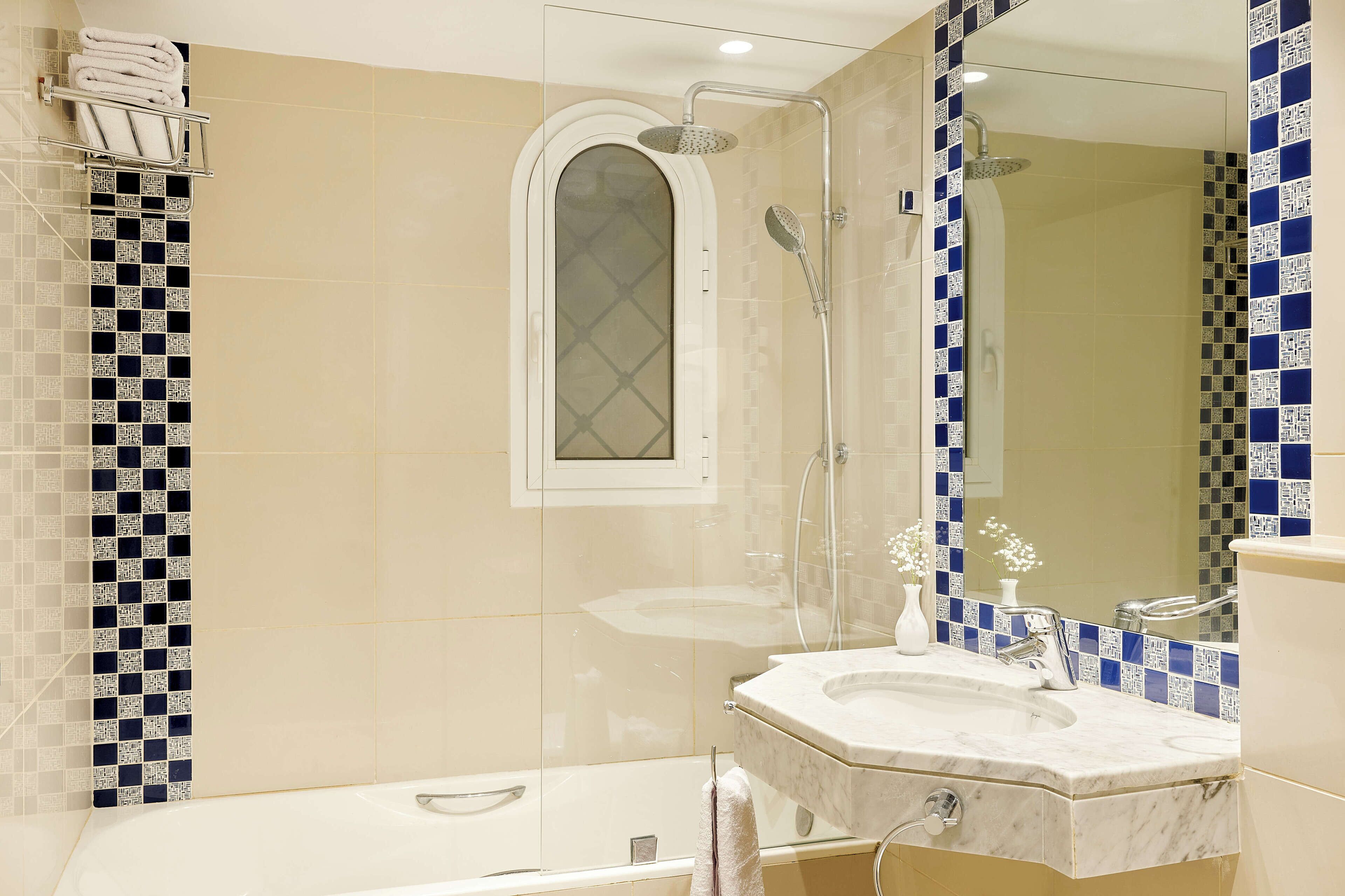Ein modernes Badezimmer mit einer Glaskabine zur Dusche, einem Waschtisch und einem Spiegel.