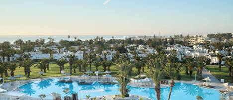 Un complexe hôtelier doté de plusieurs piscines, de palmiers et offrant une vue sur la mer.