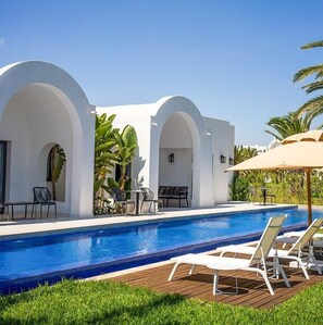 A modern pool area with white architecture, lounge chairs, and palm trees. - The Mirage Resort & SPA (Hammamet)