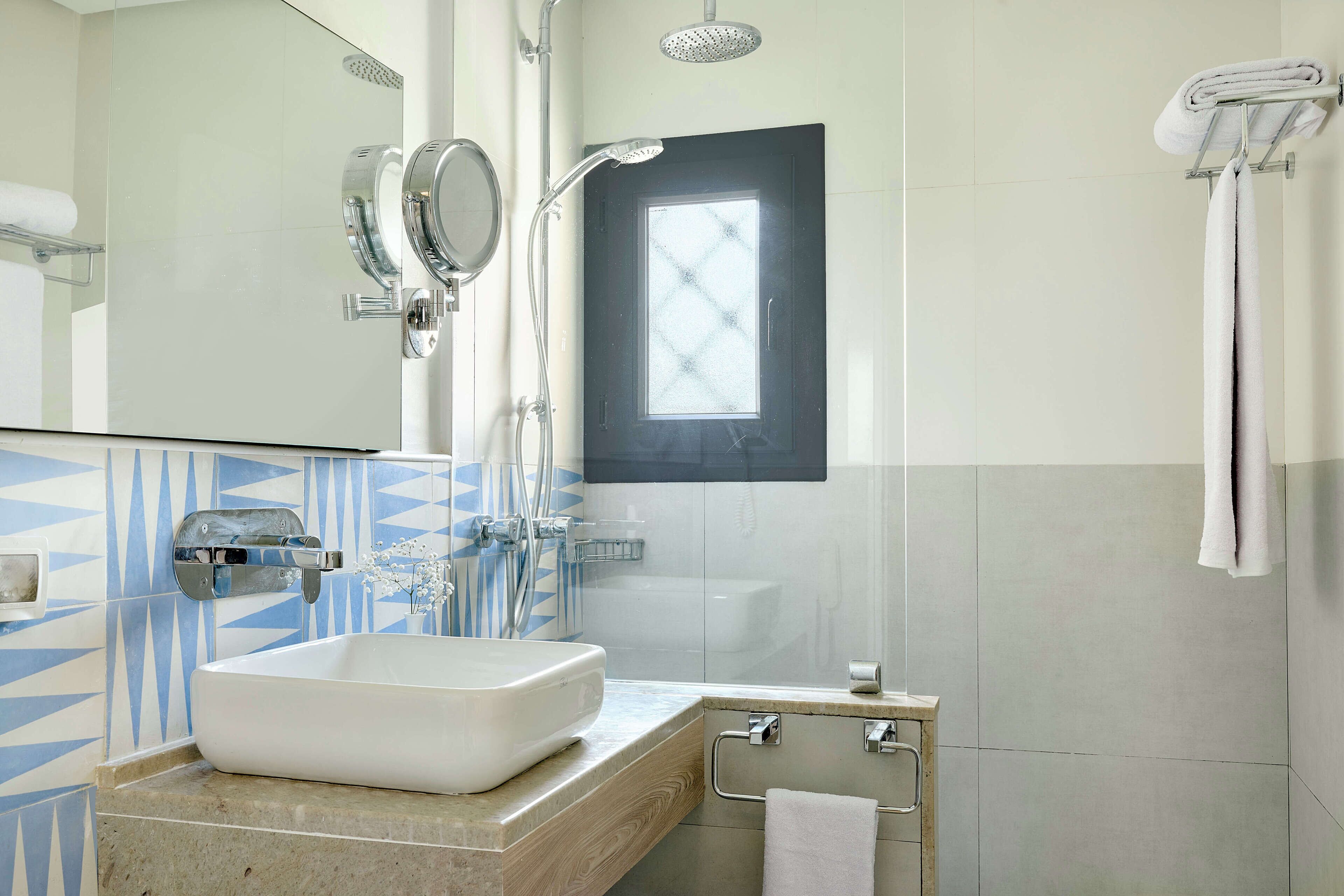 A modern bathroom with a large sink, a shower, and a window.