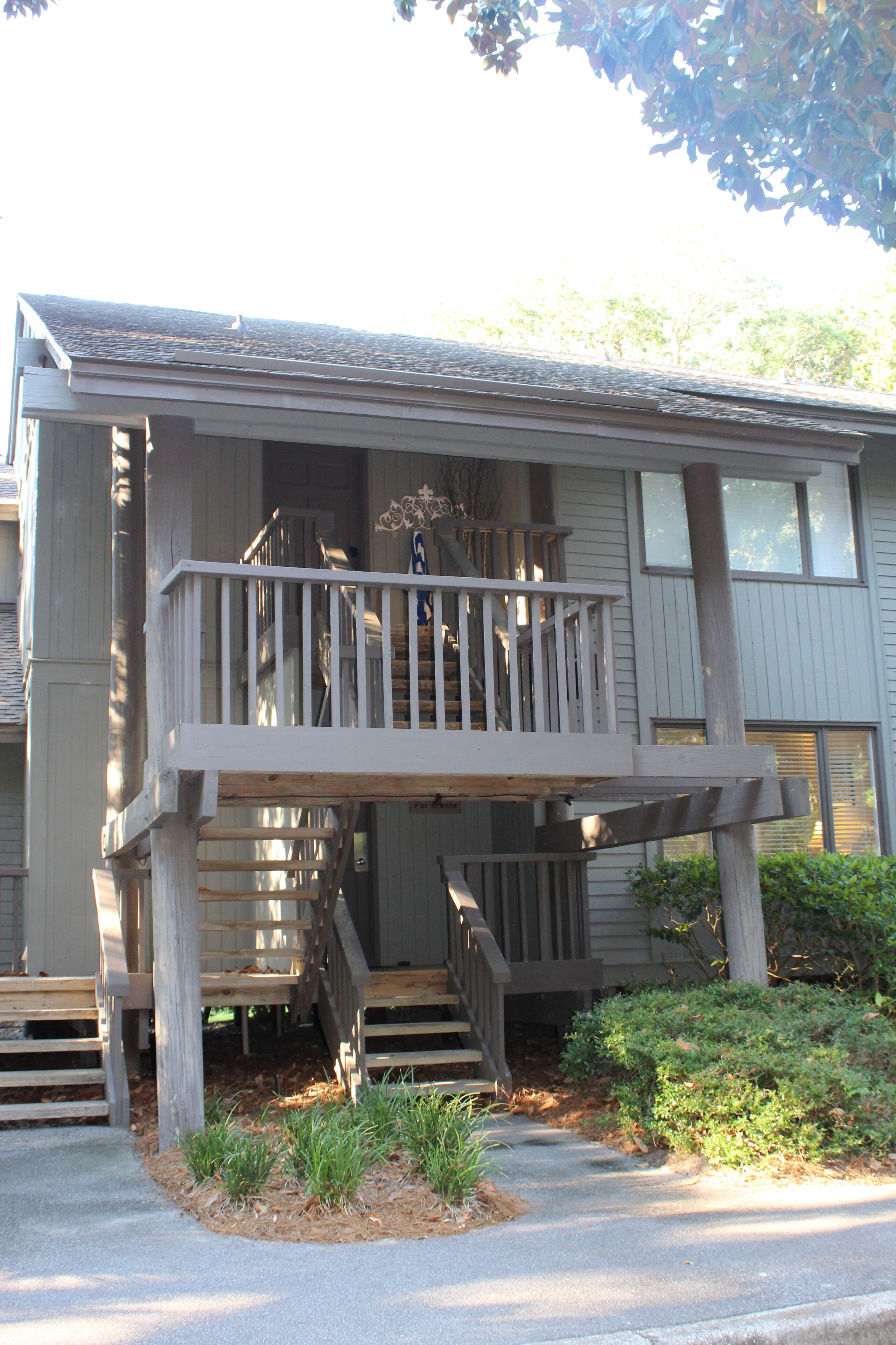 A two-story house with a wooden deck and a staircase leading to the second floor.