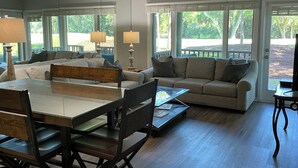 A spacious living room with a dining area, large windows, and a view of the outdoors.