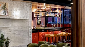 Un intérieur moderne avec un espace bar, des sièges en cuir et un mur en briques blanches.
