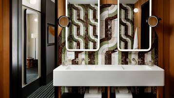 Une salle de bain moderne avec un double vasque, deux miroirs muraux et un revêtement mural décoratif en carreaux.