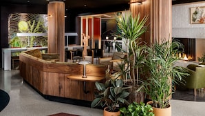Un espace d’accueil moderne, doté d’un comptoir en bois, de plantes en pot et d’un revêtement de sol au design original.