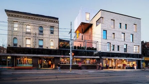 Une vue de rue avec deux bâtiments : l’un présente une façade classique, l’autre un design moderne.