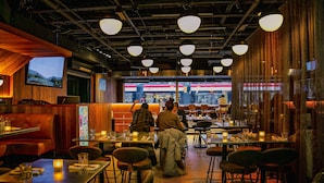 L’intérieur d’un restaurant est agrémenté de lambris en bois, de luminaires suspendus et d’une grande fenêtre donnant sur la rue.