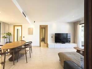 Ein modernes Wohnzimmer mit Essbereich, einem Flachbildfernseher und einer Couch.