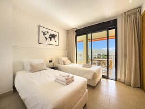 Ein Hotelzimmer mit zwei Betten, einer Weltkarte an der Wand und einem Balkon mit Tisch und Stühlen.