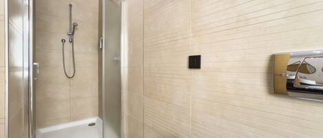 Un baño con ducha envuelta en cristal, un lavamanos blanco y un espejo con marco decorativo.