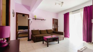 A living room with a brown sofa, a coffee table, a lamp, and a bed in the background. - Apartamento La dama de Cádiz (Cádiz)