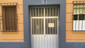 A building entrance with a white door, barred windows, and a sign indicating the address as 18 A. - Apartamento La dama de Cádiz (Cádiz)