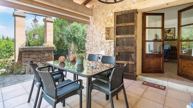 Eine Terrasse mit Glastisch und -stühlen, Steinmauern und einer Holztür.