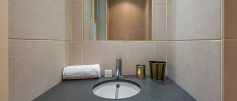 A bathroom with a sink, mirror, towel, and two containers.