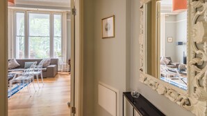 A room with a large mirror, a sofa, a coffee table, and a dining table with chairs.
